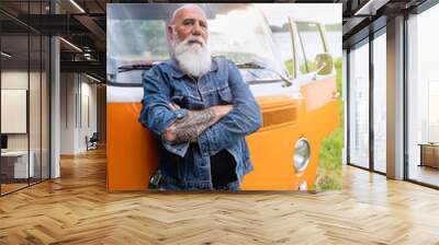 An old hipster looking at camera in front of his vintage van  Wall mural