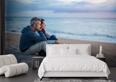 Beautiful couple sitting at the beach watching the sunset Wall mural