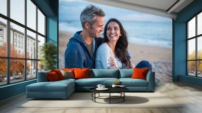 Beautiful couple sitting at the beach watching the sunset Wall mural