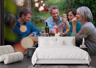 Beautiful summer evening in the garden, a group of friends in their forties have a good time laughing together around a table. Wall mural