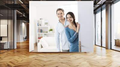 Cheerful couple inviting people to enter in home Wall mural