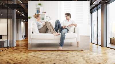 cheerful couple reading books on couch Wall mural