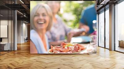 Close-up on a hand serving a dish of dry ham and cheese to friends gathered around a table in a garden to have fun together. Wall mural