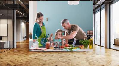 Dad, mom and their daughter cooking a recipe in the kitchen Wall mural