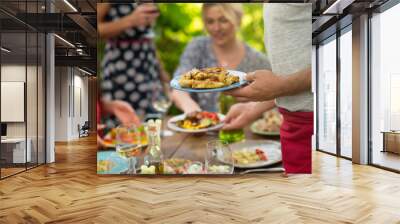 focus on hands serving dishes of food to a group of friends Wall mural