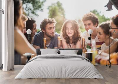 Group of young people sitting around a table outside Wall mural