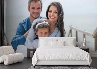 happy family sitting on a wooden pontoon in front of the sea Wall mural