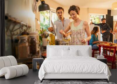 Mixed group of friends have fun while cooking a meal in kitchen Wall mural