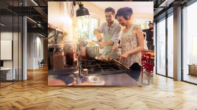 Mixed group of friends have fun while cooking a meal in kitchen Wall mural