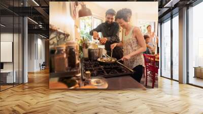 Mixed group of friends have fun while cooking a meal in kitchen Wall mural