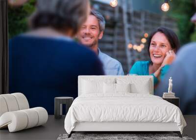 One summer evening, friends gathered around a table in the garden lit by light garlands. Focus on beautiful couple Wall mural