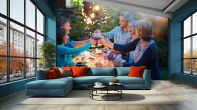 One summer evening, friends in their forties gathered around a table in the garden lit by luminous garlands. They toast with their glasses of wine Wall mural