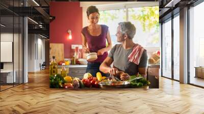 Trendy couple cooking vegetables from the market in the kitchen Wall mural