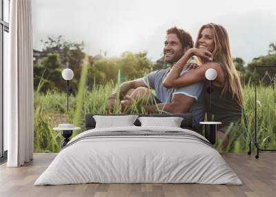 Affectionate young couple sitting on rural grass Wall mural