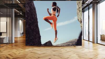 African female athlete jumping and stretching Wall mural