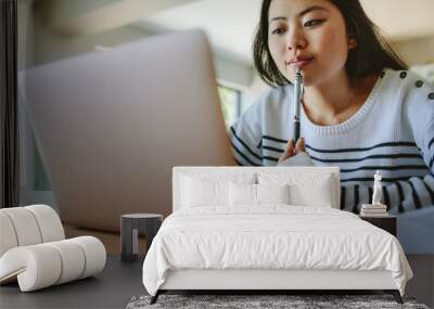 Asian woman studying at home using laptop Wall mural