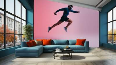 Athletic young man running mid air with virtual reality goggles Wall mural