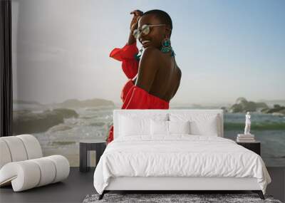 Beautiful african woman in red dress enjoying on the beach Wall mural