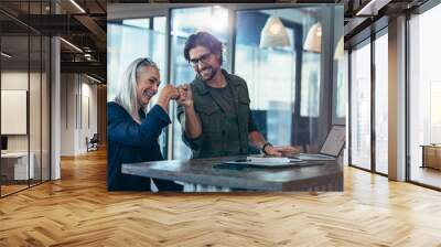 Business colleagues making a fist bump at office Wall mural