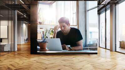 Business man thinking about a problem at his laptop Wall mural