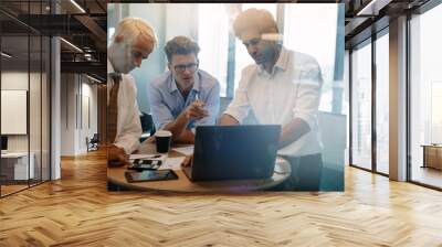 Businessman giving demonstrating on laptop to colleagues Wall mural