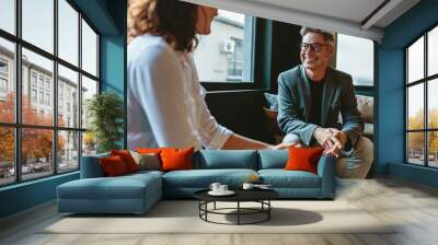 Businessman talking with female colleague in office lobby Wall mural