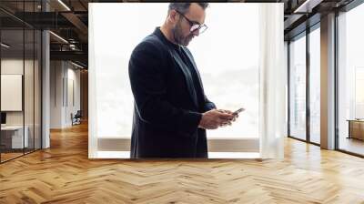 Businessman texting on mobile phone in hotel room Wall mural