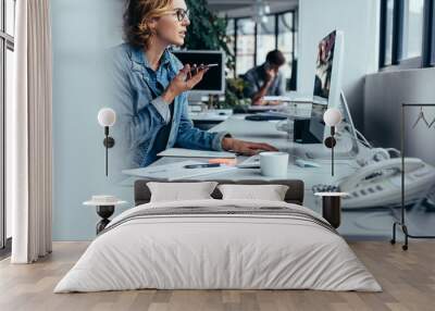 Businesswoman talking on phone and working on computer Wall mural