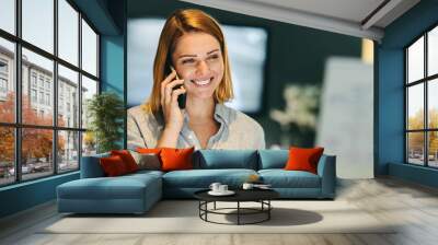 Cheerful businesswoman speaking on a phone call in an office Wall mural