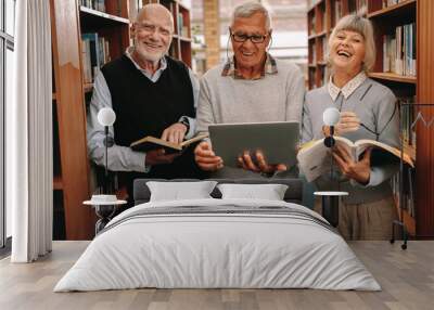 Cheerful senior colleagues standing in a library Wall mural