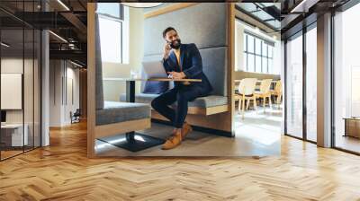 Cheerful young entrepreneur speaking on a phone call Wall mural