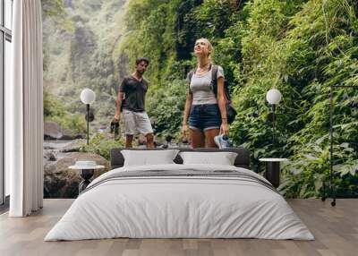 Couple on forest hike walking by a creek Wall mural