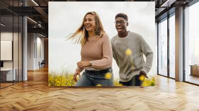 Couple playing and running through a meadow Wall mural