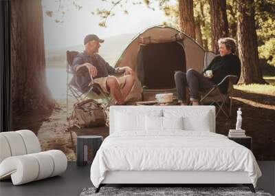 Couple relaxing on chairs by tent at campsite Wall mural