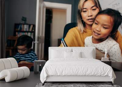 Curious little girl looking at her mom write notes in her home office Wall mural