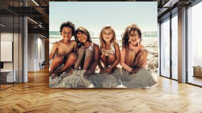 Cute kids sitting in sea sand at the beach Wall mural