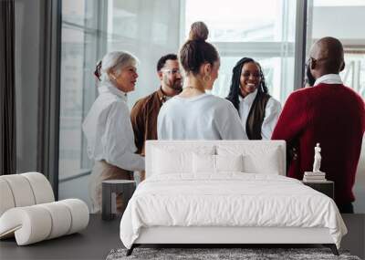 Diverse business colleagues engaging in conversation during a conference in a modern office setting Wall mural