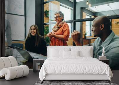 Diverse businesspeople smiling cheerfully during an office meeting Wall mural