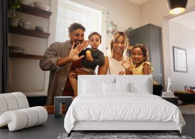 Diverse family waving during a video call at home Wall mural