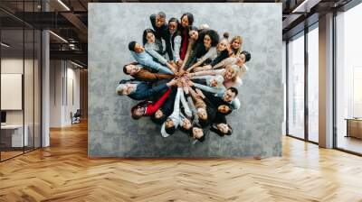 Diverse team of people joining hands in a collaborative business setting Wall mural