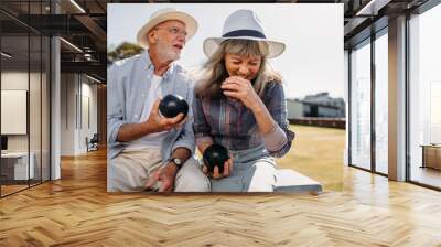 Elderly couple having fun sitting at a park holding boules Wall mural