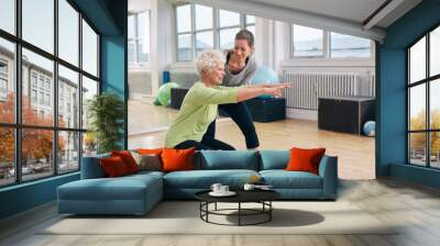 elderly woman doing exercise with her personal trainer Wall mural