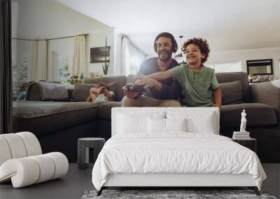 Father and son having fun at home playing video game Wall mural