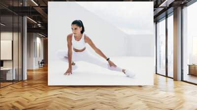 Female athlete doing warm up exercises Wall mural