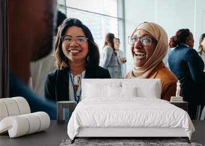 Female colleagues interacting at a corporate workshop with happy smiles and engaging conversations Wall mural