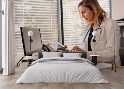 Female doctor using a tablet computer in her office Wall mural