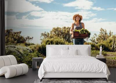 female farmer walking through the field with fresh harvest Wall mural