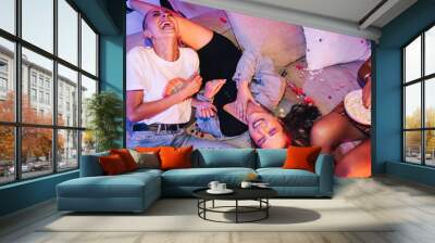 Female friends laughing hysterically at a house party Wall mural