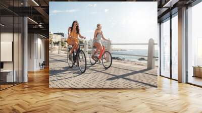 female friends riding their bicycles on the promenade Wall mural