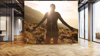 Female hiker embracing the sun light Wall mural